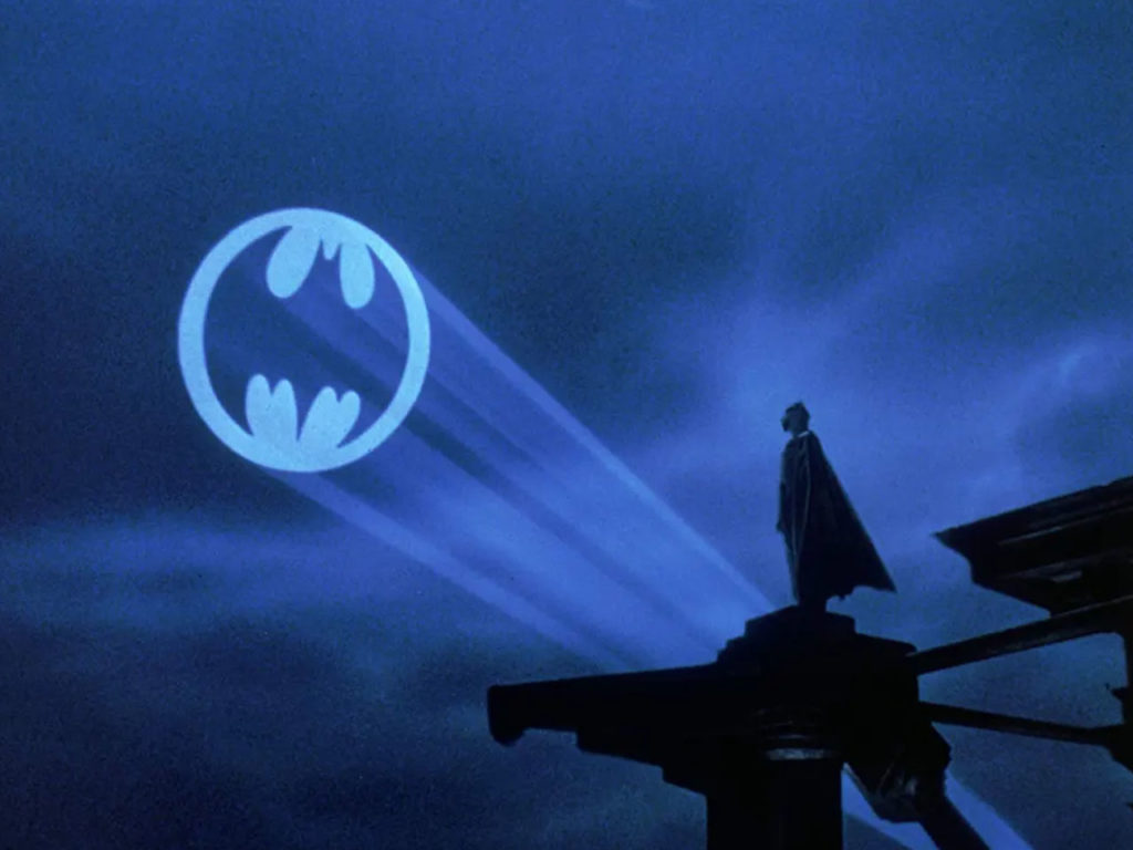Batman stands silhouetted against the Bat-Signal in Gotham City in Batman (1989)