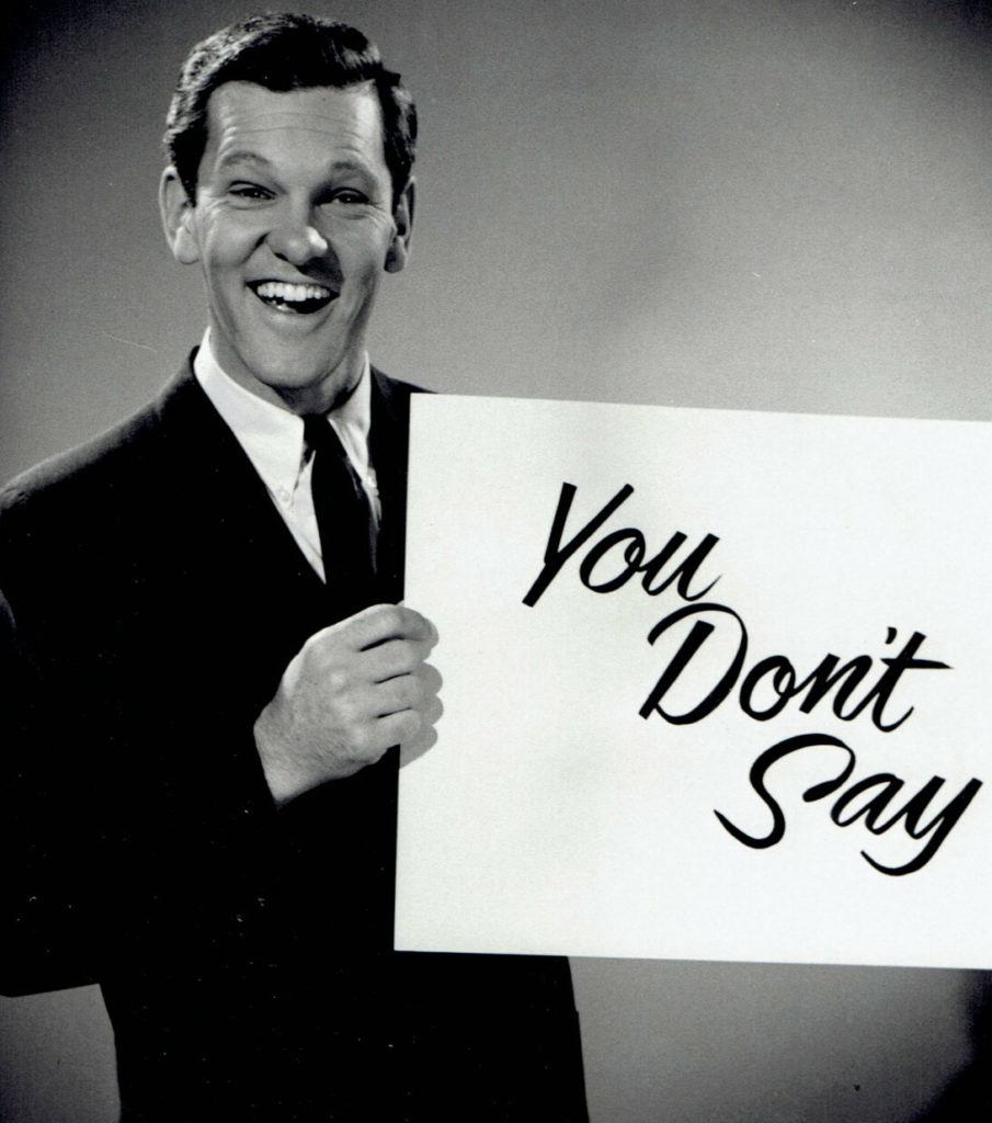 Tom Kennedy behind podium in 1960s game show You Don’t Say