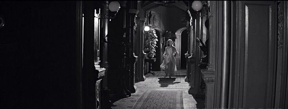 Underrated 1960s Movies - A woman standing in a shadowy hallway in The Haunting