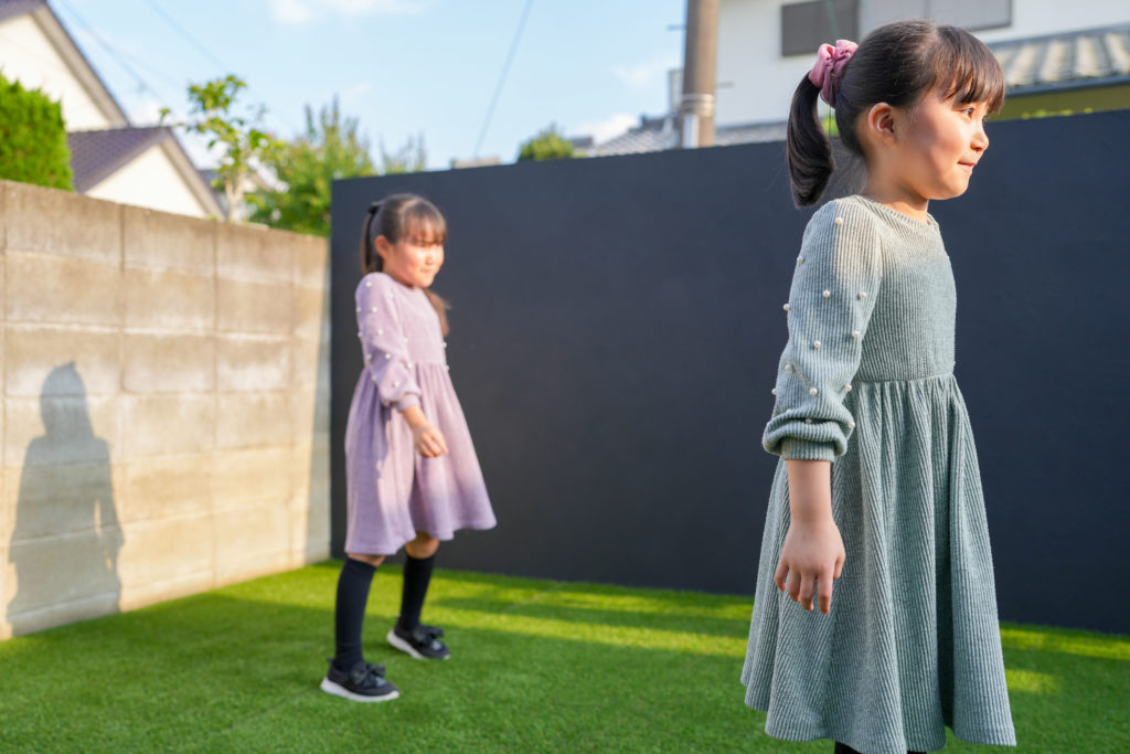 Two young girls stand on green grass