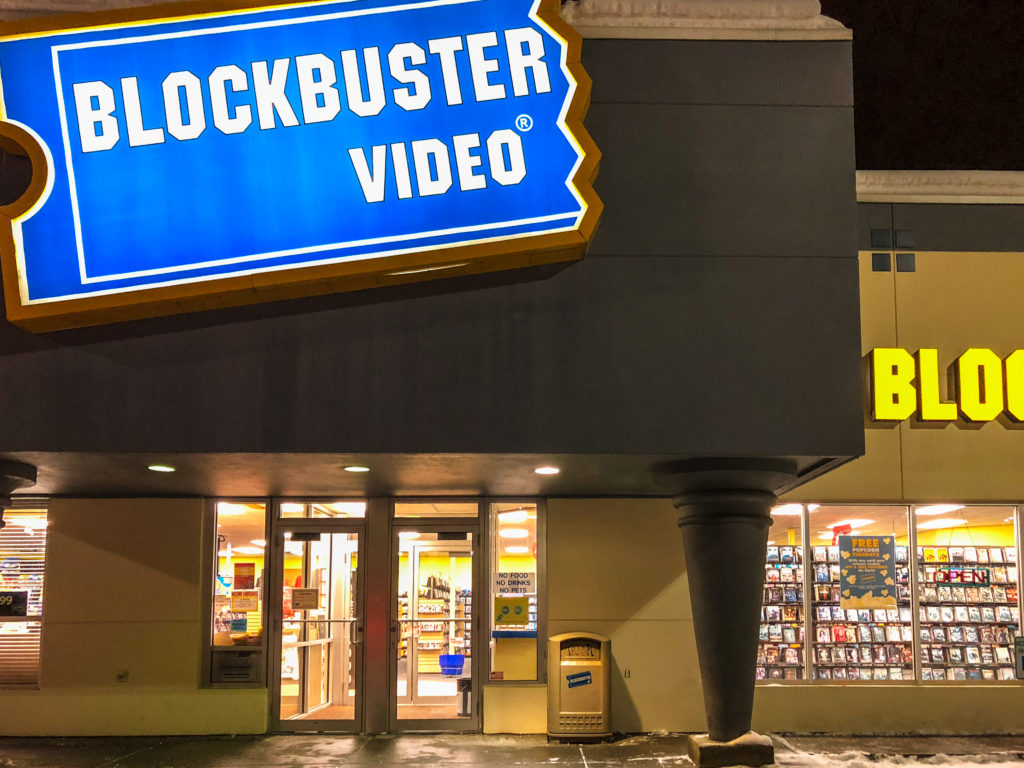 Why Blockbuster Video Became So Dominant and How It Fell - A classic exterior view of a brightly lit Blockbuster Video store at night